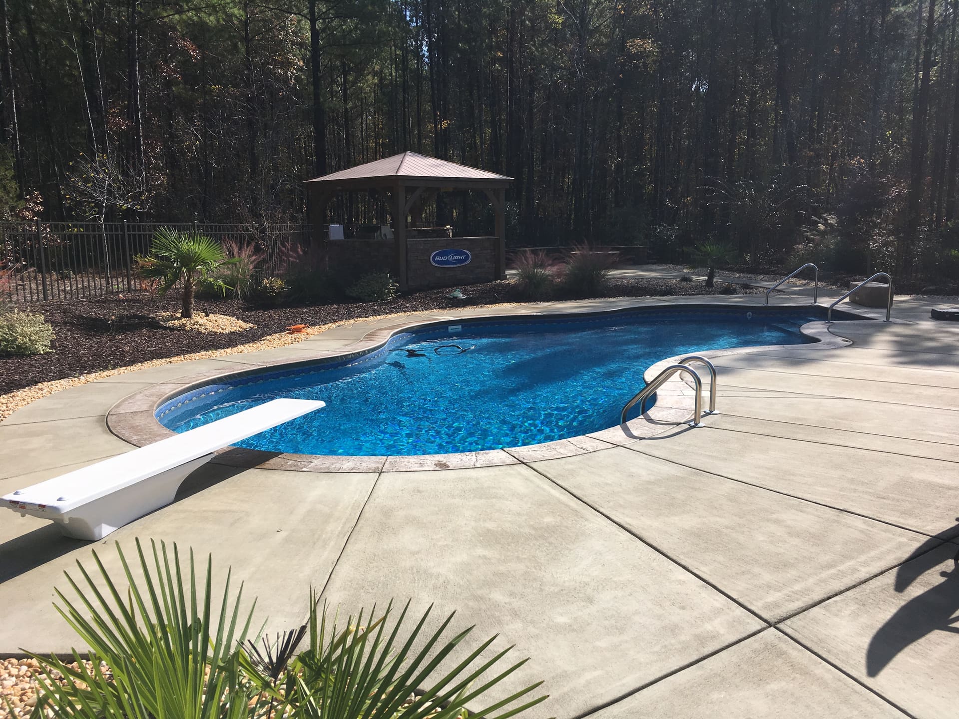 A backyard pool with a diving board and gazebo, seen from the deck